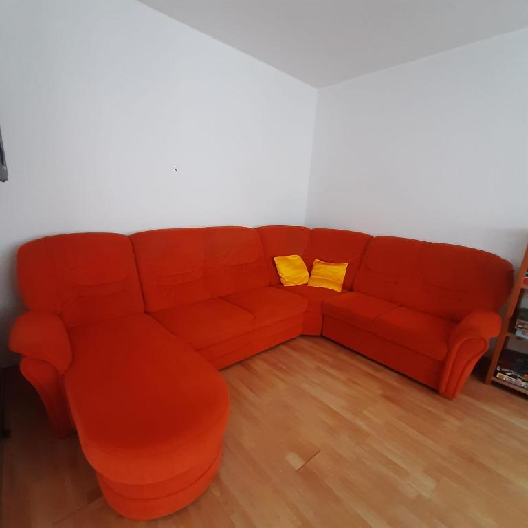 FeWo Dis في زيتز: أريكة برتقالية مع وسادتين صفراء في الغرفة
