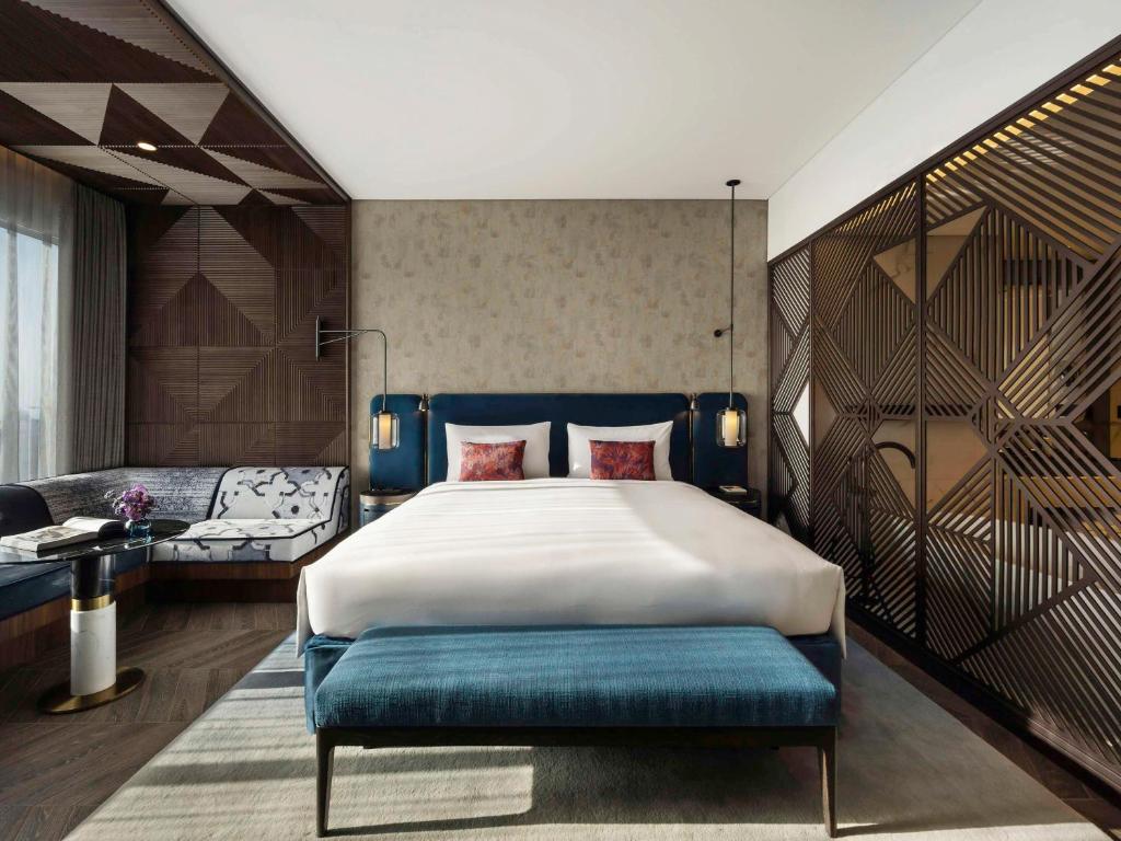 a bedroom with a large bed with a blue bench at SO/ Uptown Dubai in Dubai
