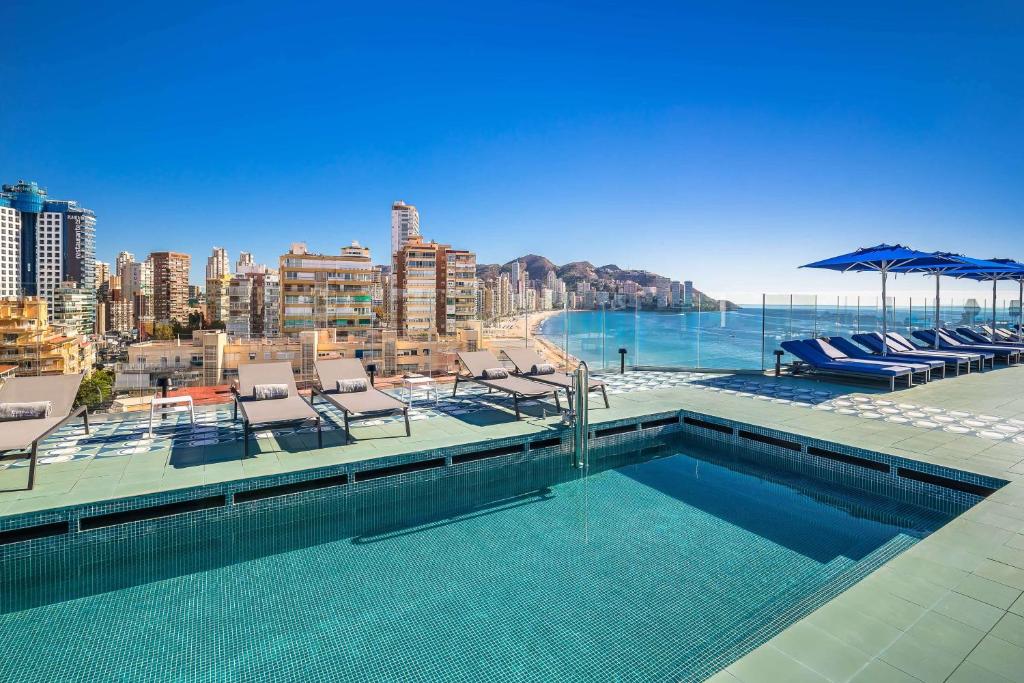a swimming pool with chairs and a view of the city at Barceló Benidorm Beach - Adults Recommended in Benidorm