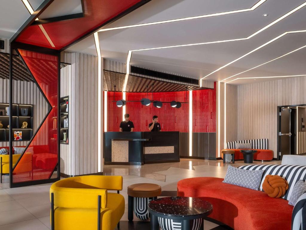 a lobby with yellow and red furniture and a bar at TRIBE Living Bangkok Sukhumvit 39 in Bangkok