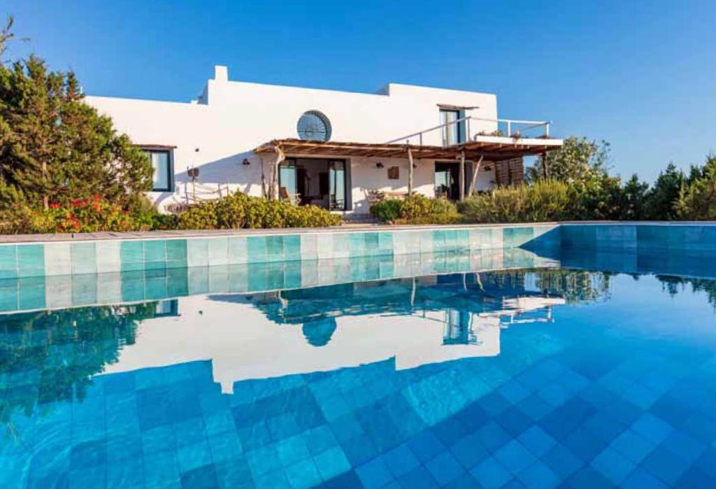 a villa with a swimming pool in front of a house at Can Piedrópolis in Cala Saona