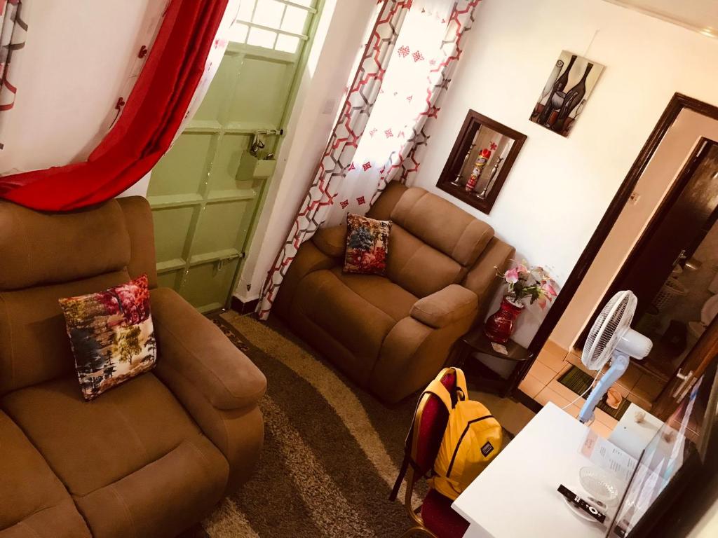salon z 2 krzesłami i kanapą w obiekcie Stone Island w mieście Kisumu