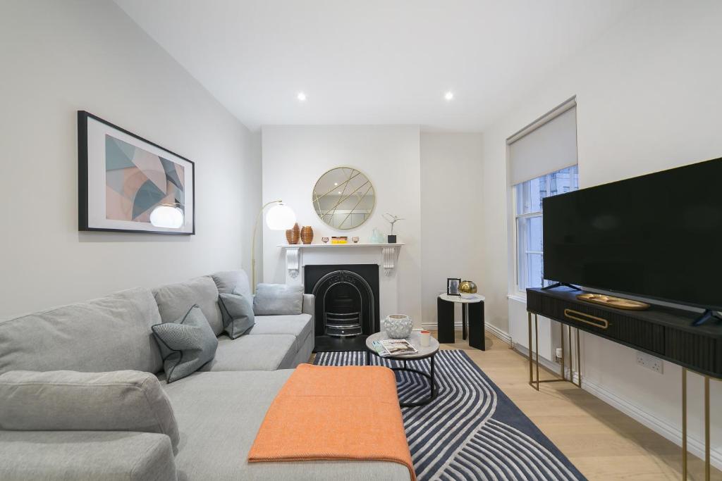salon z kanapą i telewizorem z płaskim ekranem w obiekcie Urban Chic - Acre w Londynie