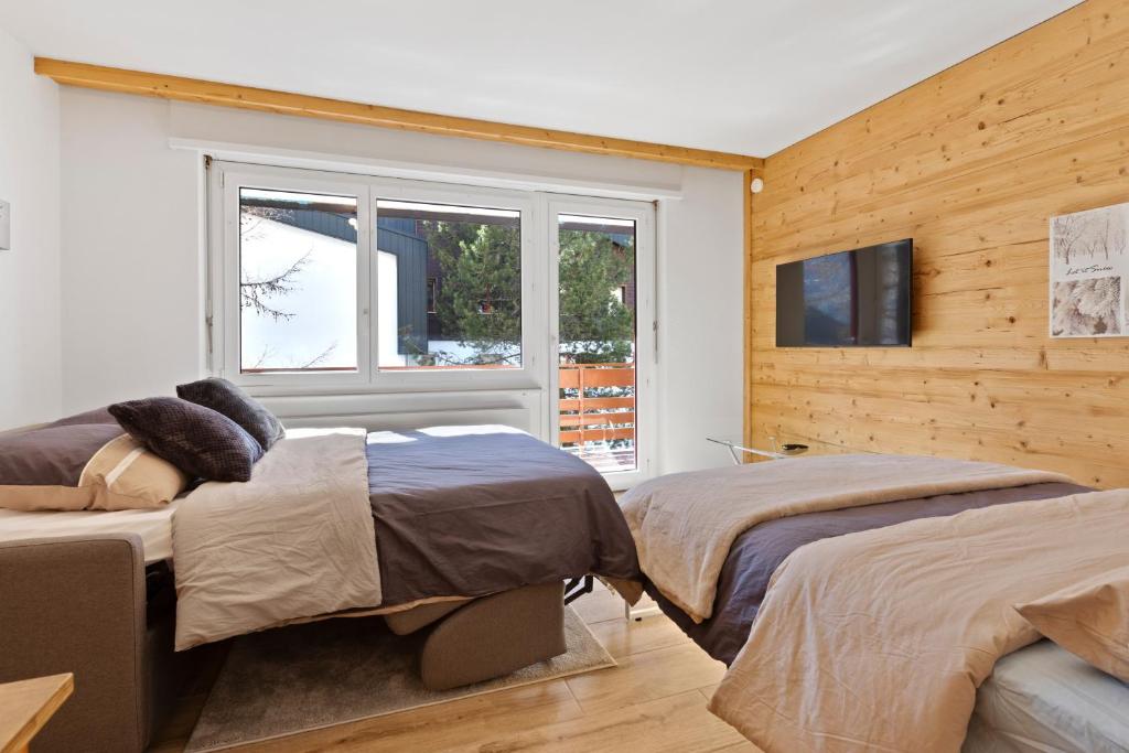 a bedroom with two beds and a window at Retraite alpine, studio paisible et rénové in Leukerbad