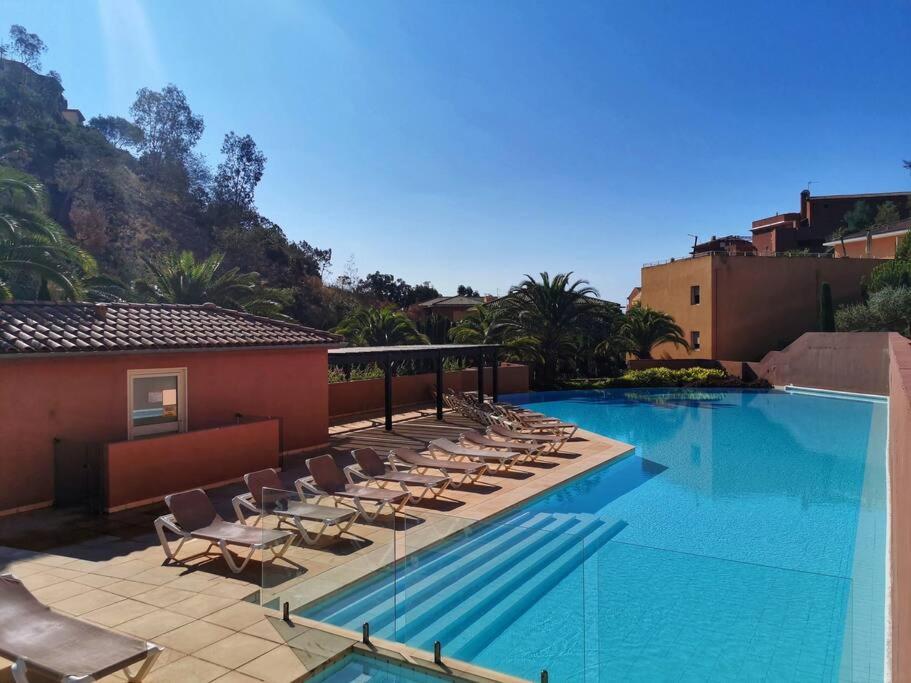 une piscine avec des chaises longues à côté d'un bâtiment dans l'établissement Elégant 3 pièces au Port de la Figueirette, à Théoule-sur-Mer