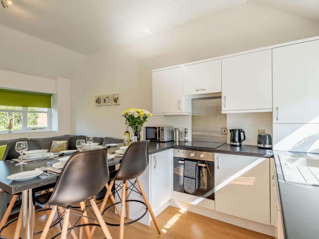 una cocina con armarios blancos y una mesa con sillas. en 2 Bed in Louth 86797, en Louth