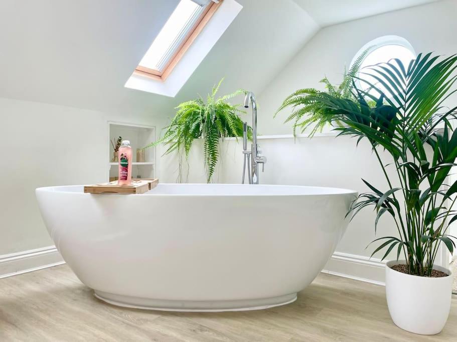 a white bath tub in a bathroom with two plants at Meadow Guesthouse - Private Hot Tub in Rossett