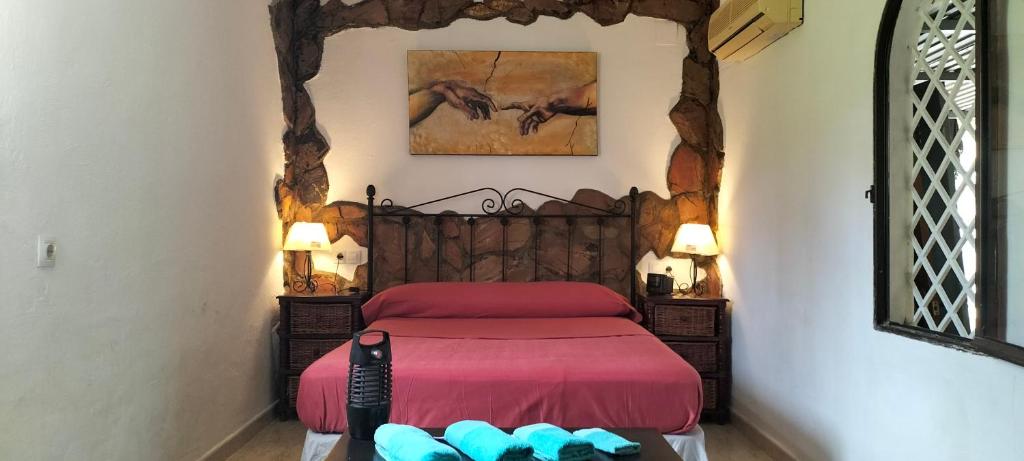 a bedroom with a bed with a red bedspread at FINCA RIODIEL in Gibraleón