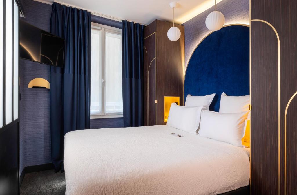 Schlafzimmer mit einem großen Bett mit blauem Kopfteil in der Unterkunft Best Western Bretagne Montparnasse in Paris