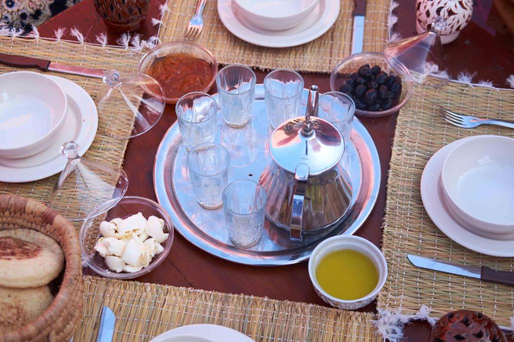 una mesa con vasos, platos y tazones de comida en Olympe Surf & Yoga en Tamraght Ouzdar