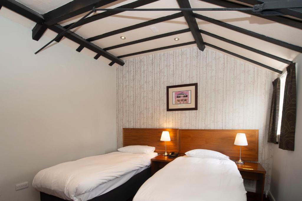 two beds in a room with white walls and black beams at The Royal Hop Pole Wetherspoon in Tewkesbury