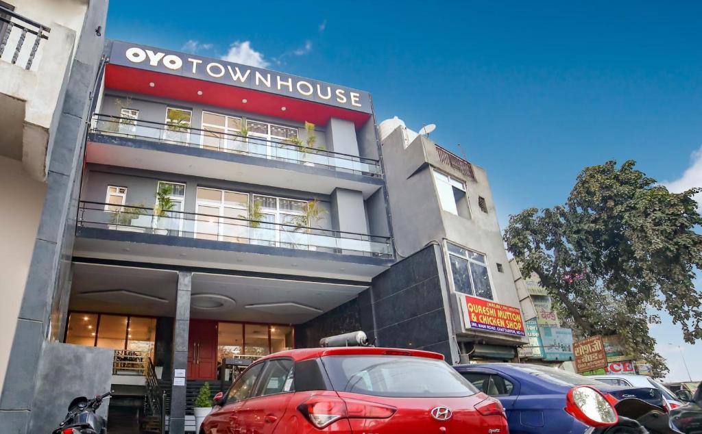 a red car parked in front of a brown house at OYO Townhouse 067 Chattarpur Opp. Tivoli Garden Near Chhatarpur Metro Station in New Delhi