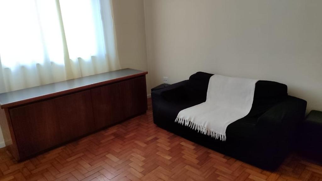 a room with a black chair and a window at 2 quartos Icaraí in Niterói