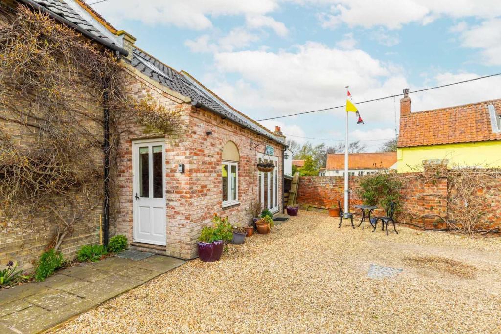 Casa de ladrillo con puerta blanca y patio en The Nest, en Wells-next-the-Sea