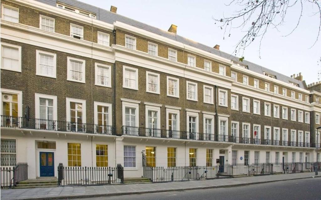 - un grand bâtiment en briques avec des portes et des fenêtres jaunes dans l'établissement Campbell House, à Londres