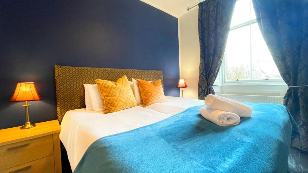 a bedroom with a bed with a blue blanket and a window at Catcune Suite - Four Bedroom Split Level Apartment in Gorebridge