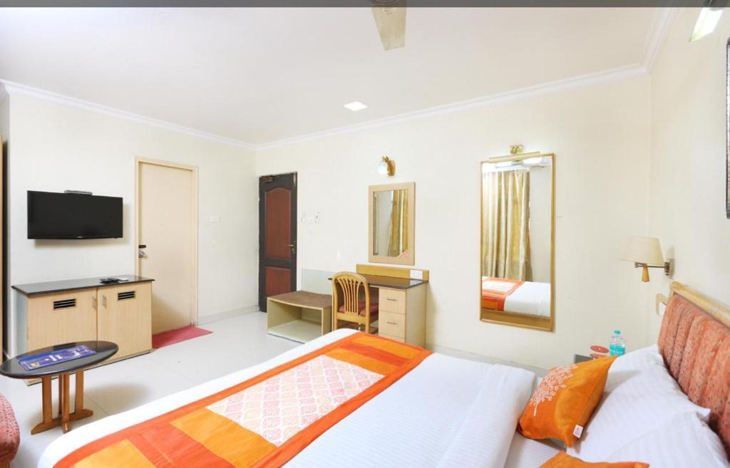 1 dormitorio con 1 cama, escritorio y TV en NakshaTree Hotels, Maruthi Residency -Mogappair, en Chennai