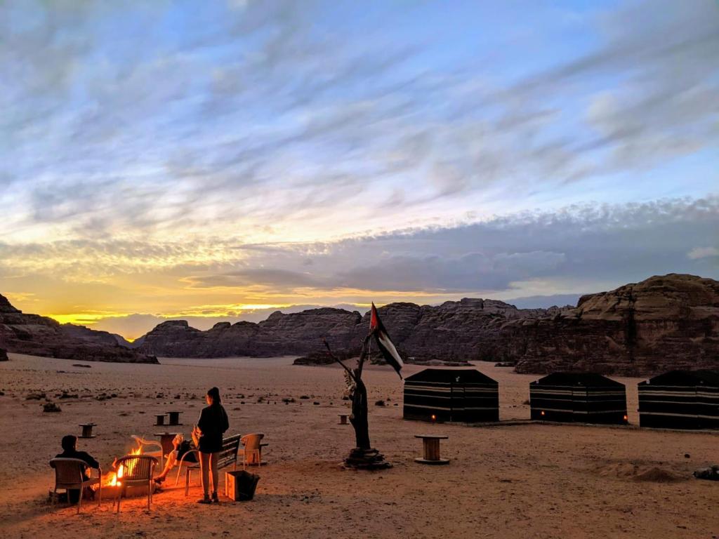 a group of people sitting around a campfire in the desert at Wadi rum galaxy camp in Wadi Rum
