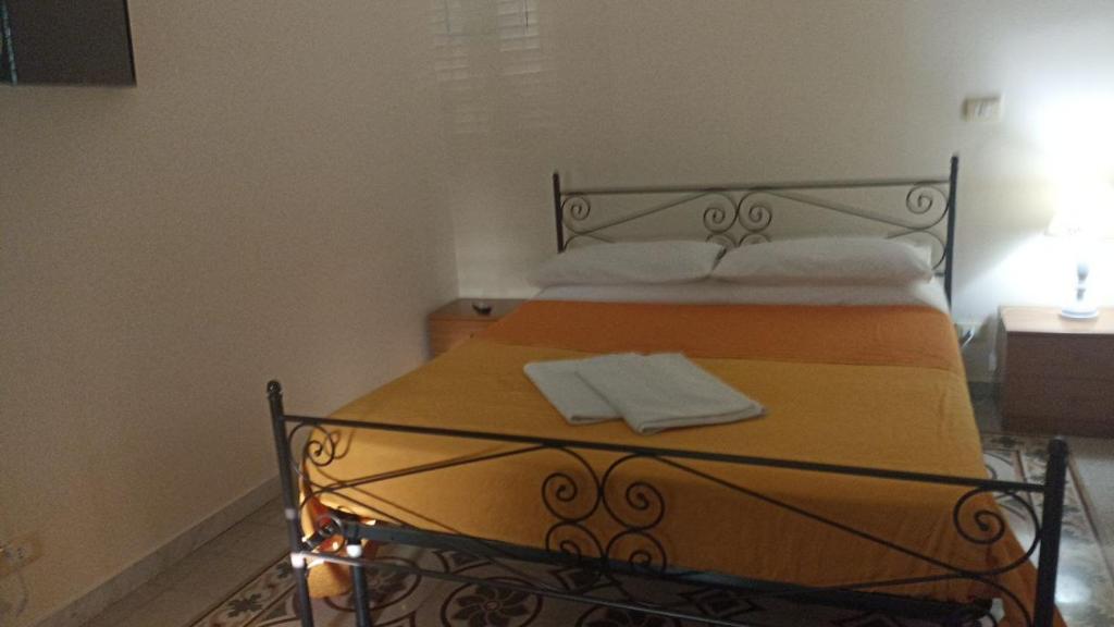ein Bett mit einer orangefarbenen Decke und weißen Kissen in der Unterkunft Casa vacanze home cecilie in Reggio di Calabria