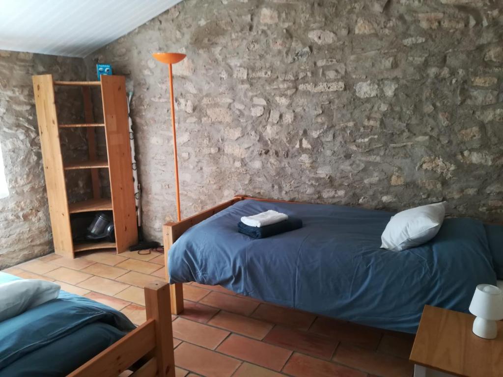 a bedroom with two beds and a stone wall at Gite un toit sur la Doa in Apt