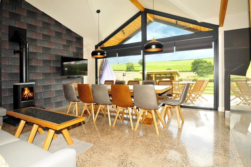 uma sala de jantar com uma mesa e cadeiras e uma lareira em Westwood Lodge em Much Wenlock