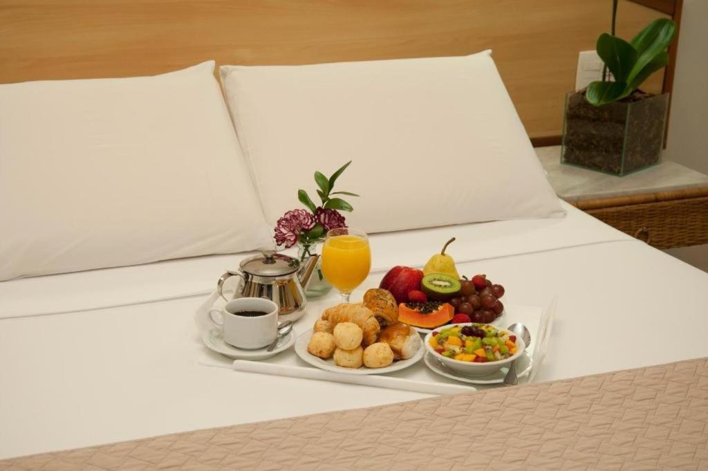 a tray of food on a bed with a breakfast at Max Savassi Apart Service in Belo Horizonte