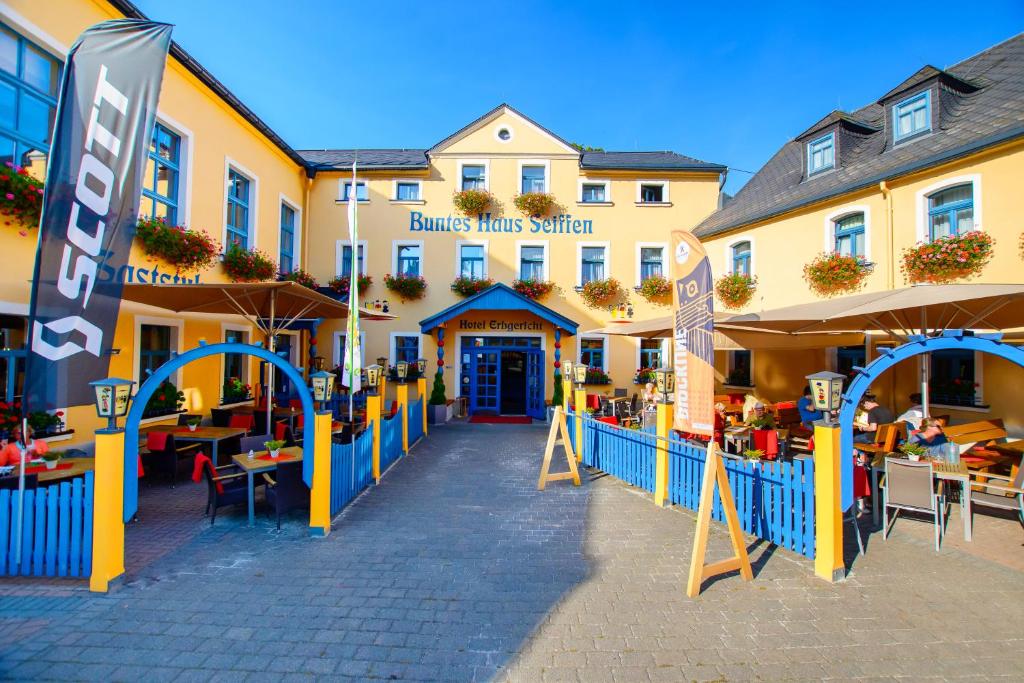 un hôtel avec des tables et des chaises devant lui dans l'établissement Hotel Erbgericht Buntes Haus, à Seiffen