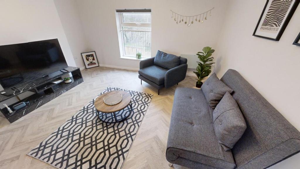 een woonkamer met een bank en stoelen en een televisie bij A Prestwich Apartments M25 in Manchester