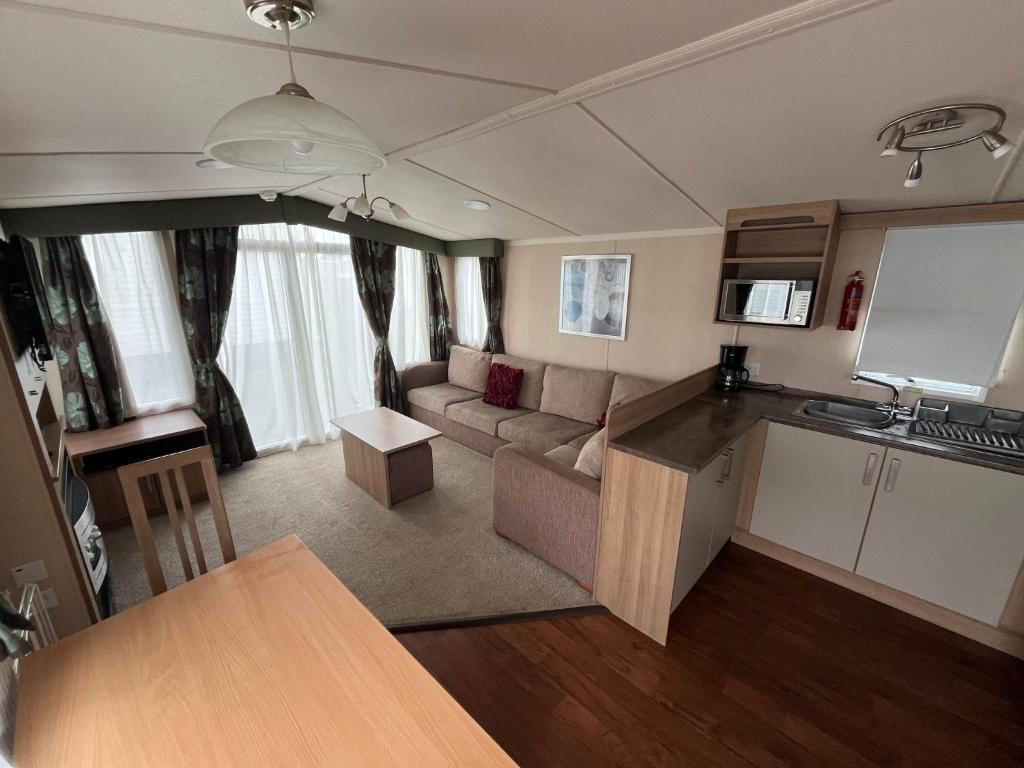 a kitchen and living room with a couch and a table at Bittern 13, Scratby - California Cliffs, Parkdean, sleeps 6, pet friendly, bed linen and towels included - close to the beach in Great Yarmouth