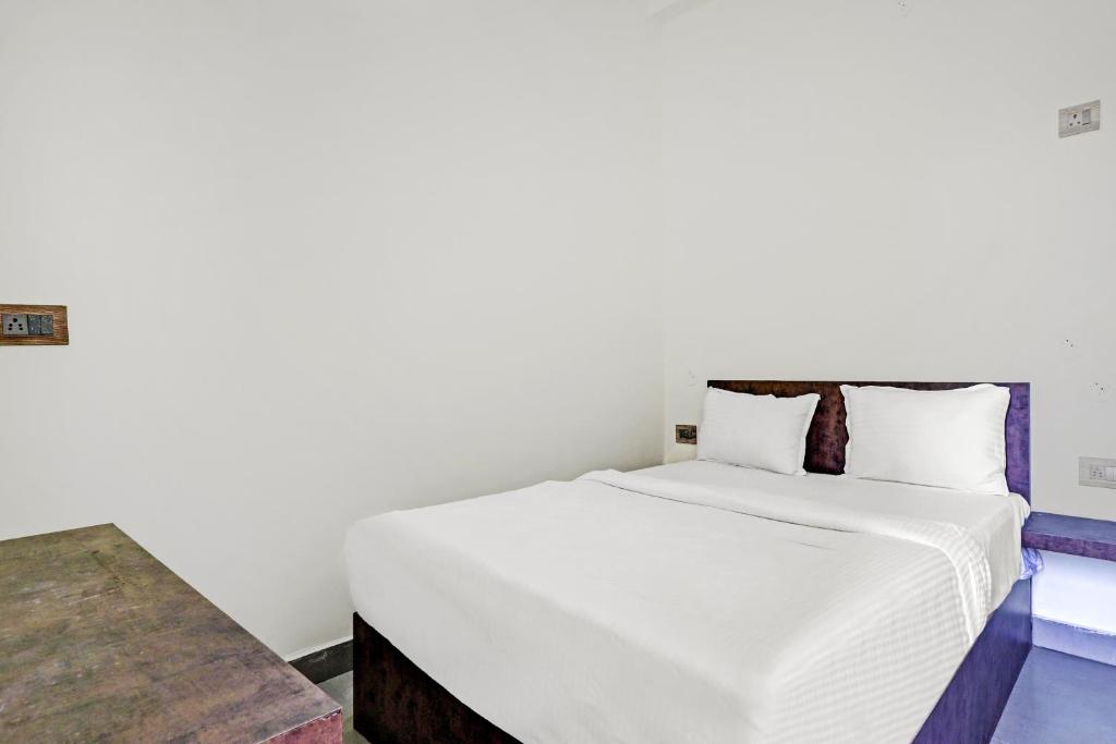 a bedroom with a white bed and a table at Collection O Hotel Dhruv Tara Inn in Patna