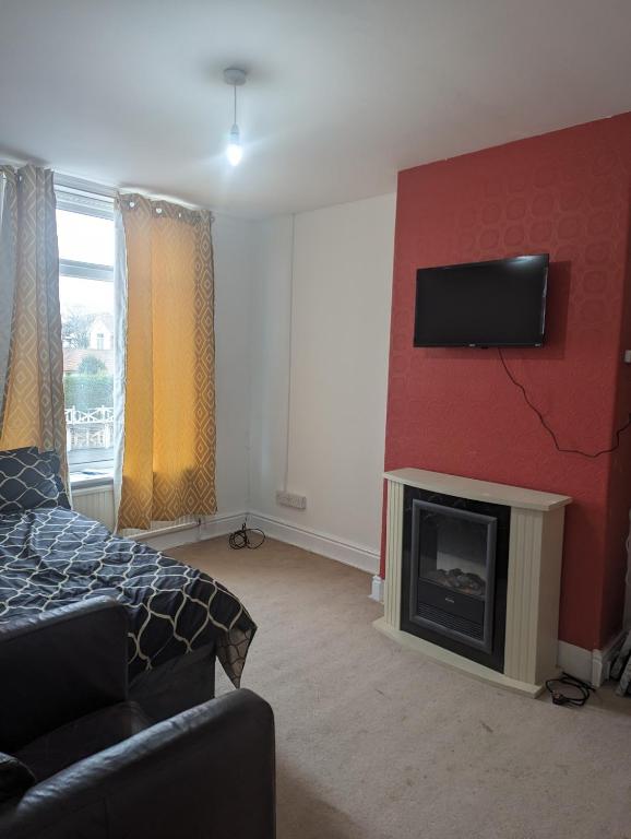 a living room with a bed and a tv on a wall at Little Guesthouse in Cleveleys