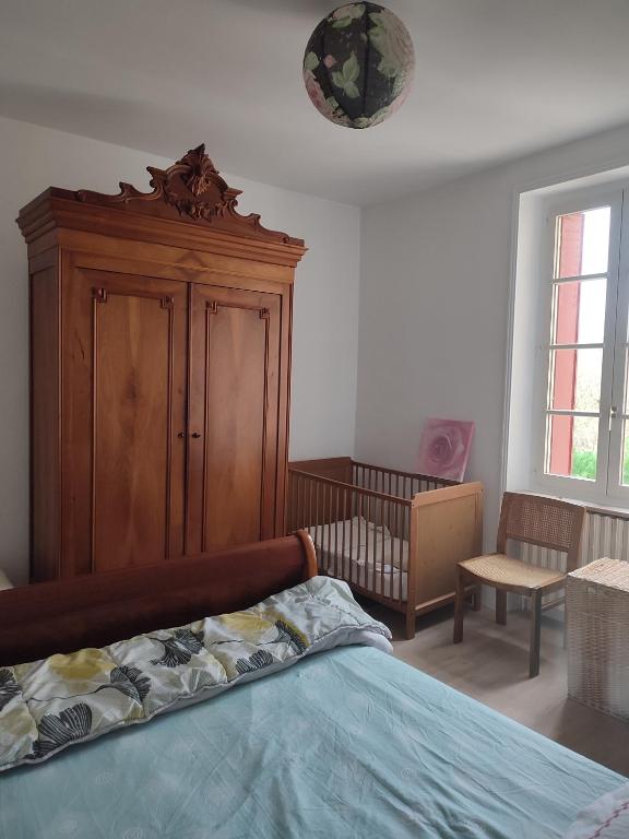 une chambre avec un lit et une armoire en bois dans l'établissement Maison à 3 chambres, rustique, fraîche, entretenue, 15' zoo beauval commerces pharmacie route médiane, à Luçay-le-Mâle