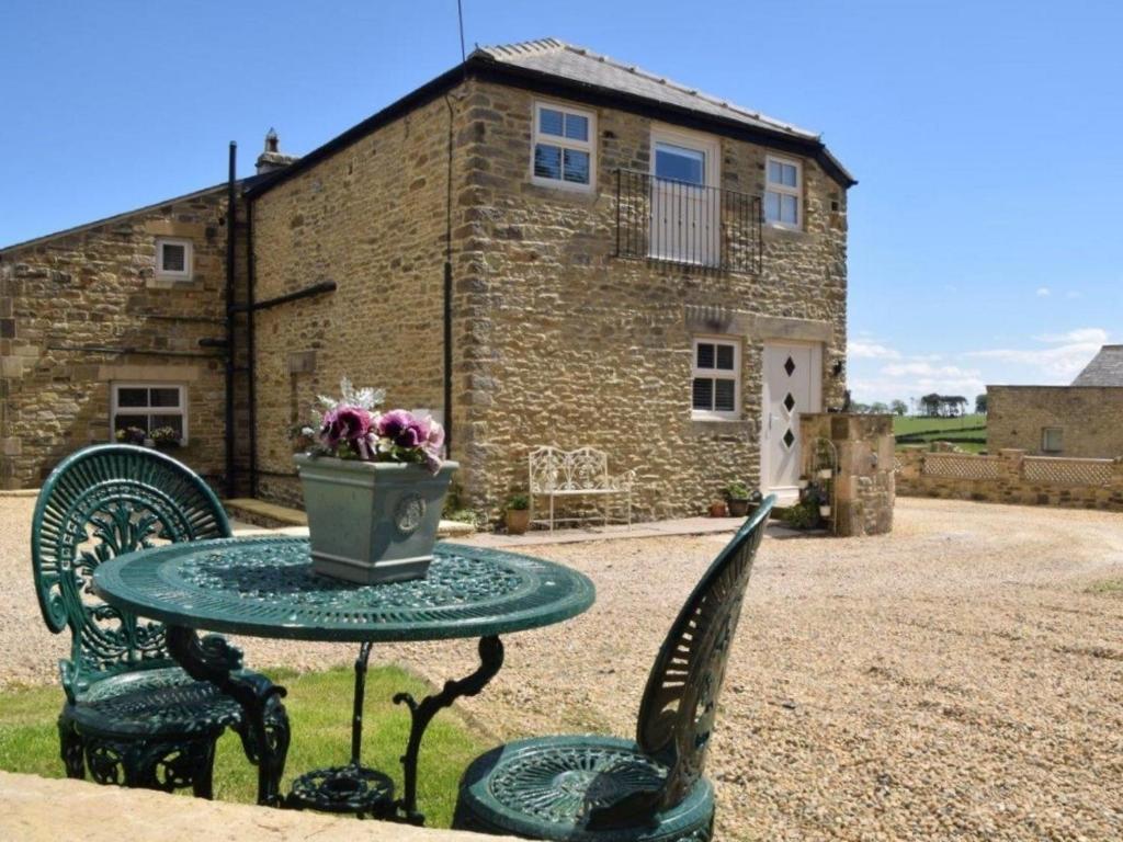 a table with a vase of flowers on it in front of a building at 1 Bed in Durham 76615 in Lanchester