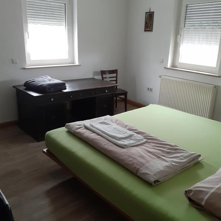 a bedroom with a green bed and a desk at Backstubencafe Beck in Ansbach