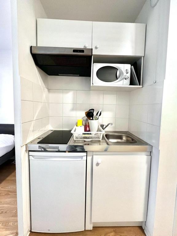 eine kleine Küche mit weißen Schränken und einem Waschbecken in der Unterkunft Résidence Hôtelière Le Prado in Libourne