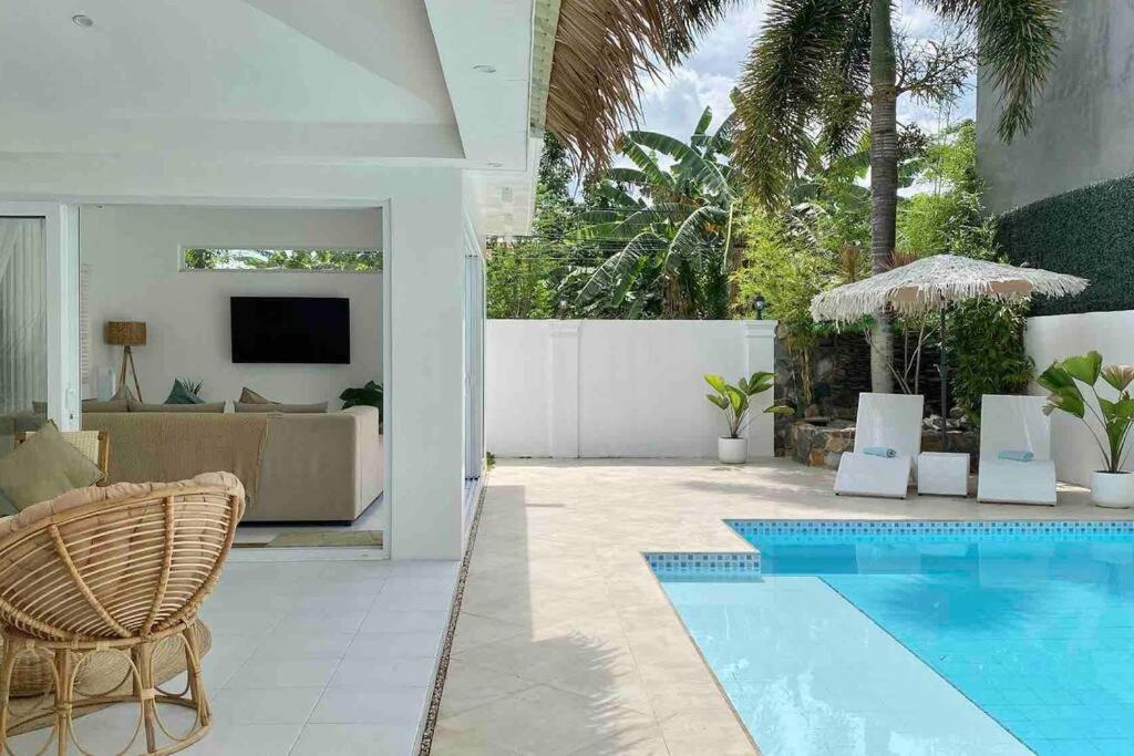 a living room with a swimming pool and a house at The White Villa in Lipa in Lipa
