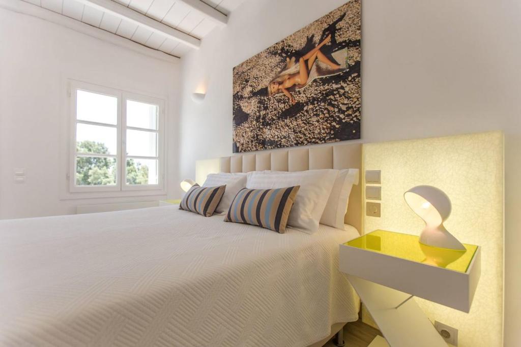 a white bedroom with a white bed and a window at Fortan 5* villa in Mýkonos City