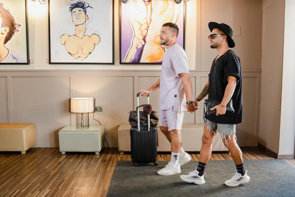 twee mannen lopen in een kamer met een koffer bij The Purple Hotel - Adults Only in San Antonio