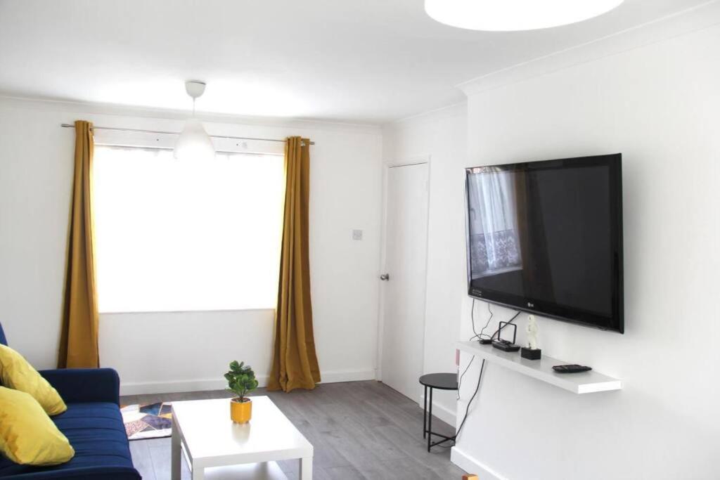 a living room with a blue couch and a flat screen tv at Coolfin House - London Excel in London