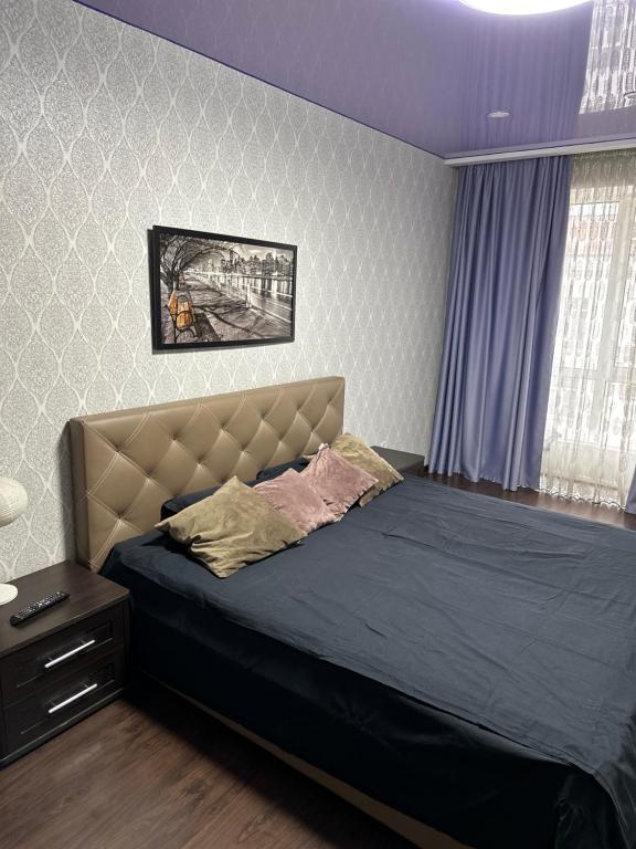 Schlafzimmer mit einem großen Bett mit blauer Tagesdecke in der Unterkunft Sweet Home in Dnipro
