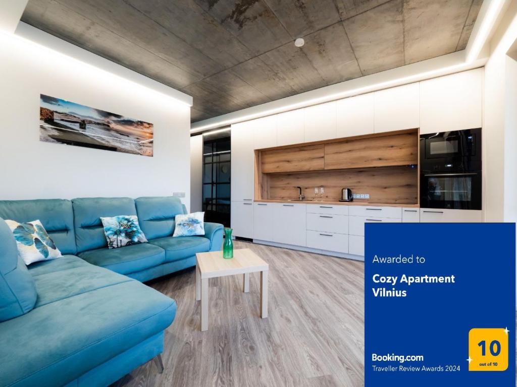 a living room with a blue couch and a kitchen at Cozy Apartment Vilnius in Vilnius