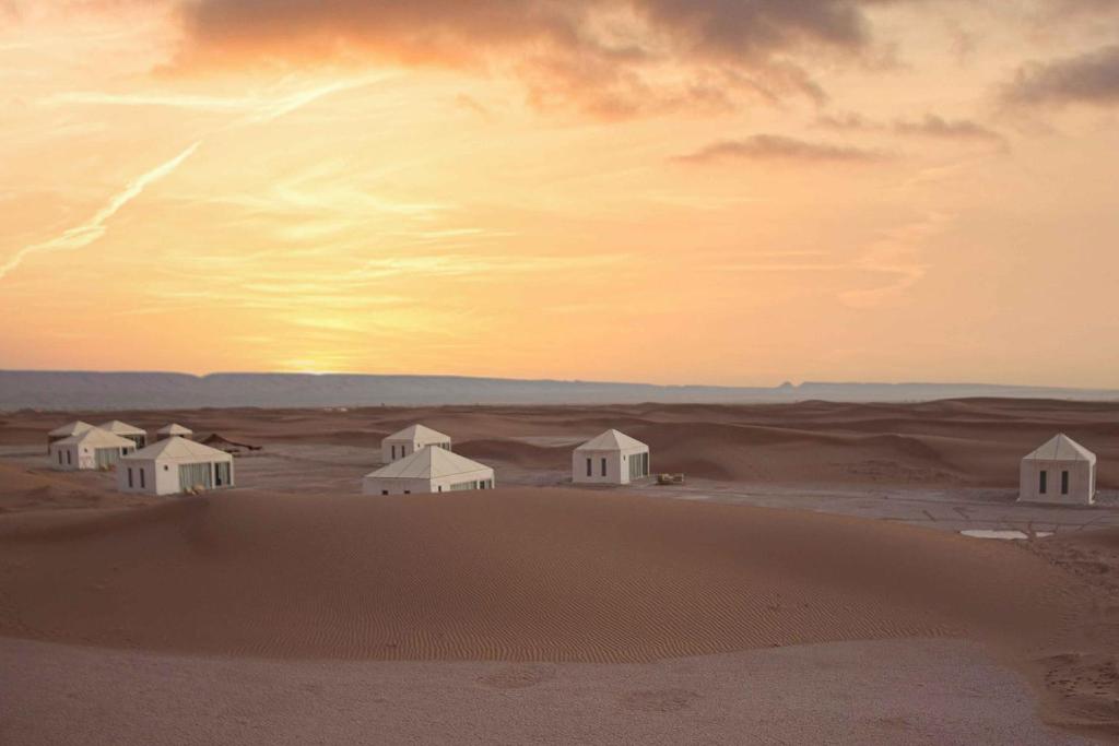 a group of white huts in the desert at Ghazala Camp in Mhamid