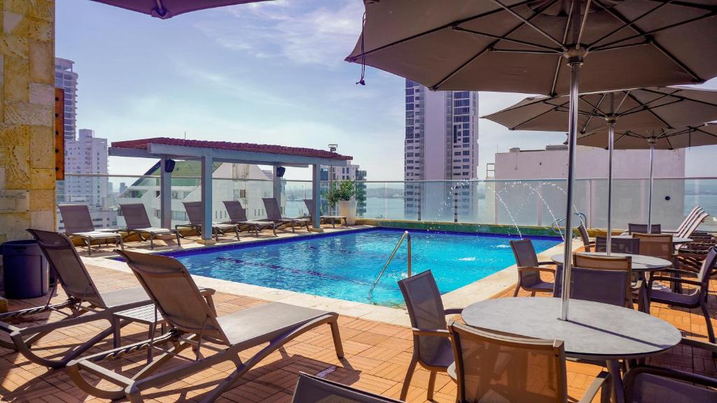 um pátio com mesas e cadeiras e uma piscina num edifício em Hotel Capilla del Mar em Cartagena das Índias