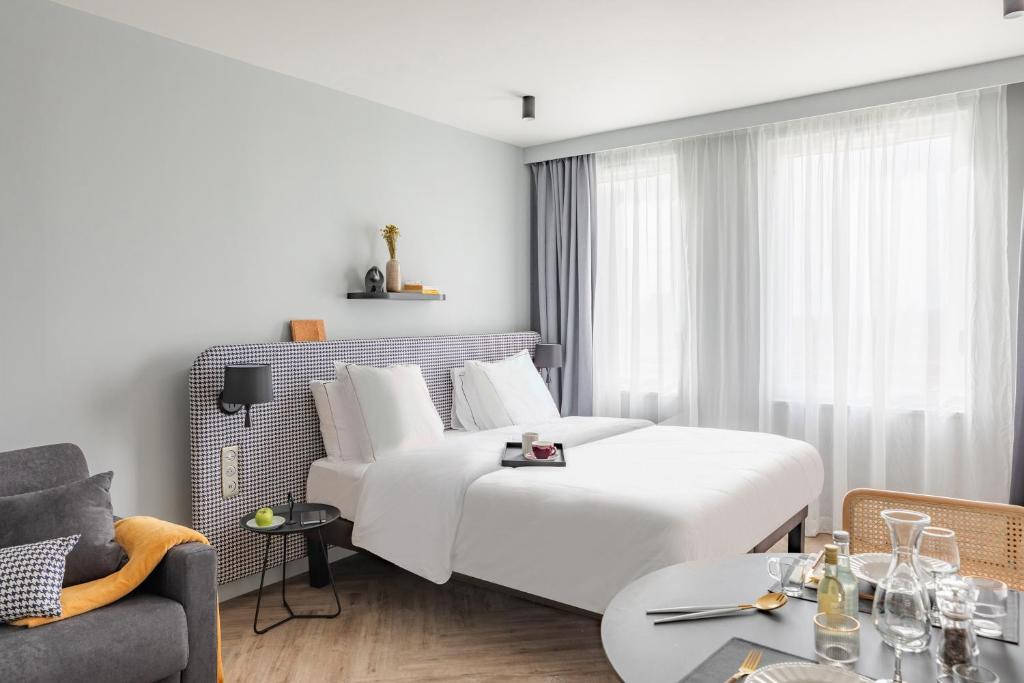 ロワシー・アン・フランスにあるAppart'City Collection Paris Roissy CDG Airportのベッドとテーブルが備わるホテルルームです。