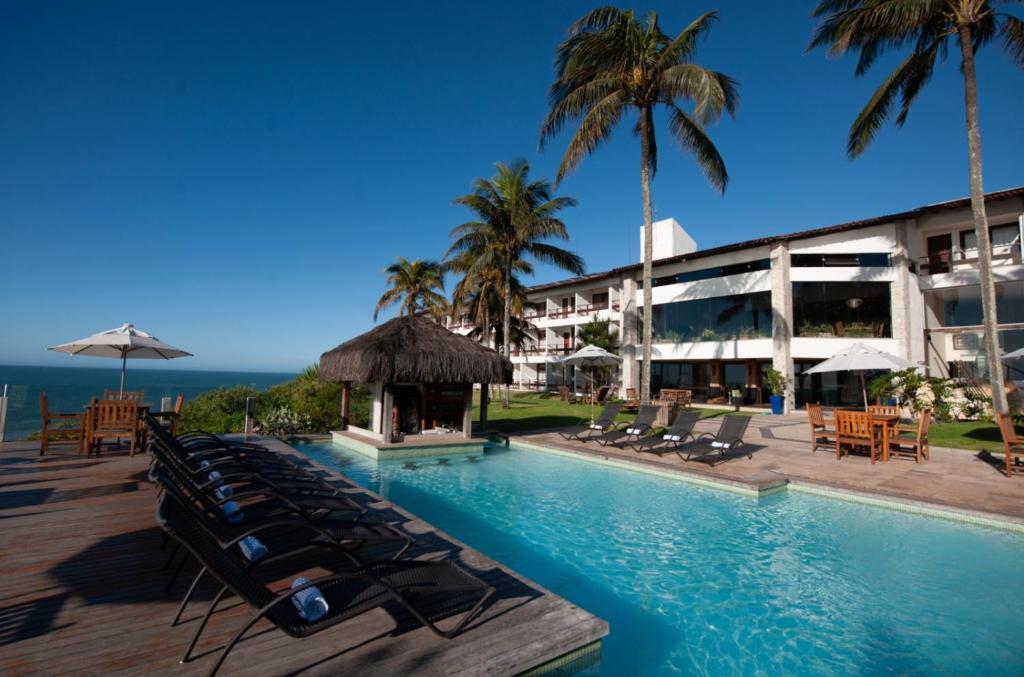 ein Resort mit einem Pool, Stühlen und Palmen in der Unterkunft Hotel Pontal de Ubu in Anchieta