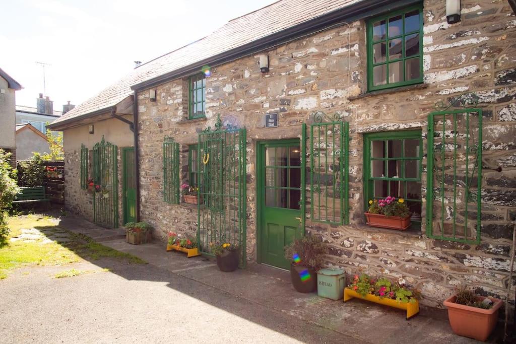 une ancienne maison en pierre avec des volets verts et des plantes dans l'établissement Yr Hen Efail - Old Smithy, à Tregaron