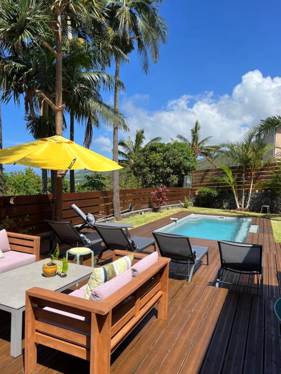 una terraza con mesa, sillas y piscina en Maison avec piscine chauffée - 8 personnes - Sud Réunion en Saint-Joseph