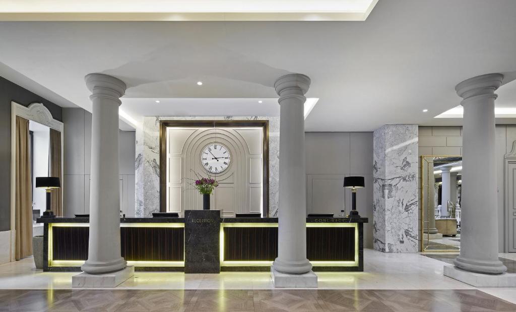 a lobby with columns and a clock on the wall at TITANIC Gendarmenmarkt Berlin in Berlin