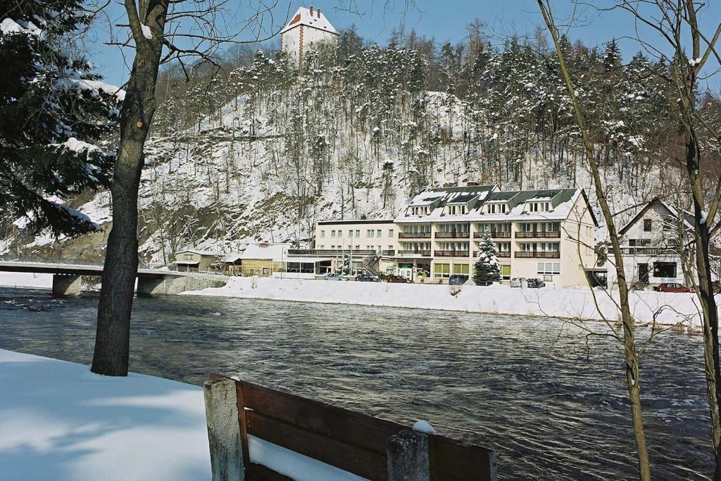 a bench next to a river with a mountain at Hotel Am Schlossberg in Ziegenrück
