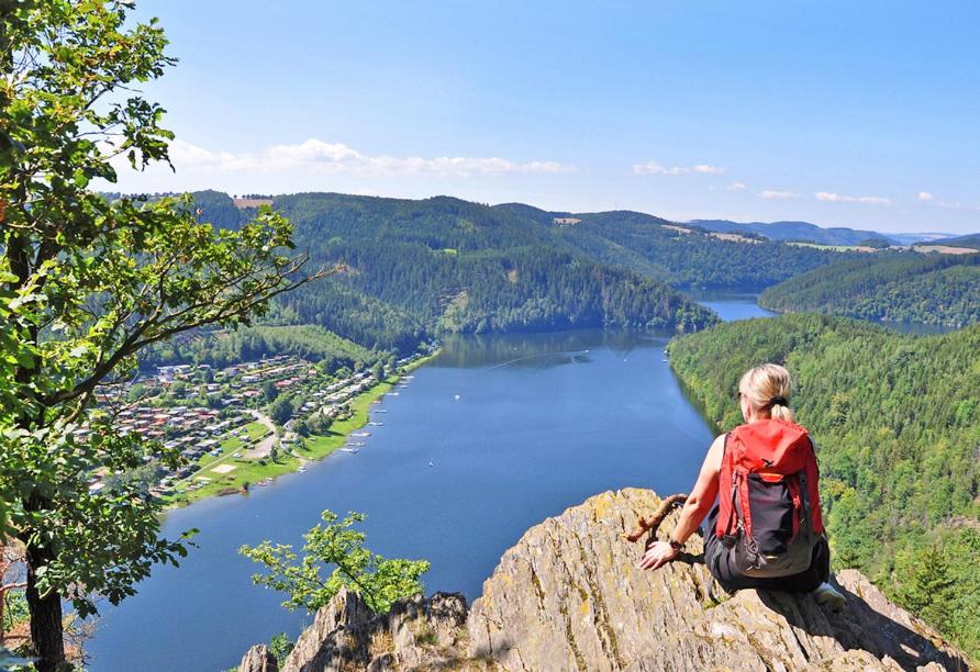a person sitting on a rock overlooking a lake at Hotel Am Schlossberg in Ziegenrück